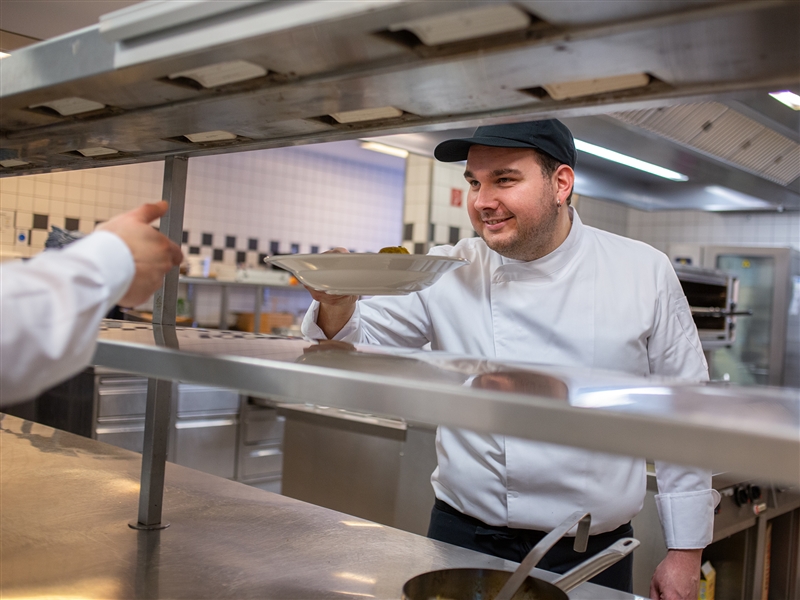 Den fertig angerichteten Teller an das Restaurant ausgeben