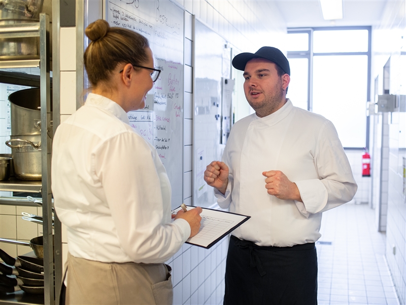 Den Tagesplan mit einer Restaurantmitarbeiterin absprechen
