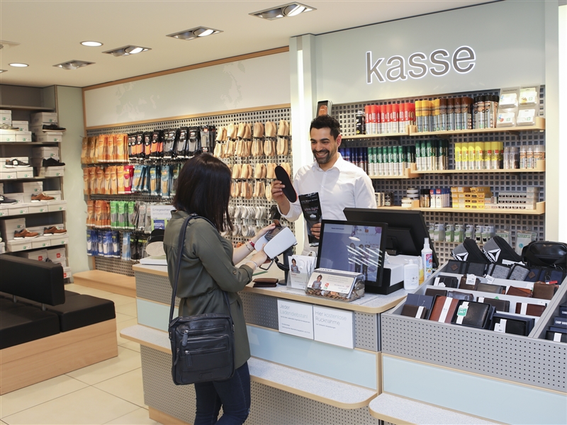 Im Kassenbereich für die Kundin die gekaufte Ware einpacken