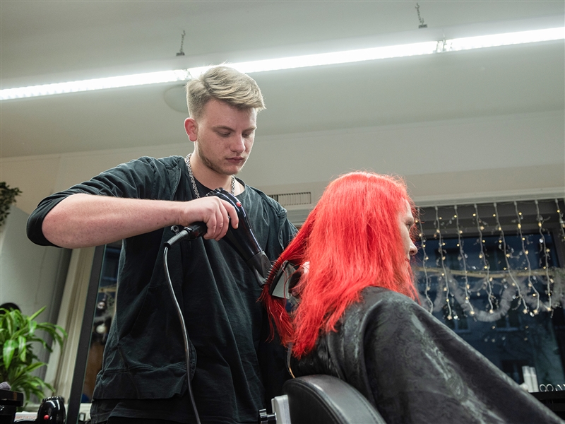Haare einer Kundin föhnen und zur gewünschten Frisur stylen